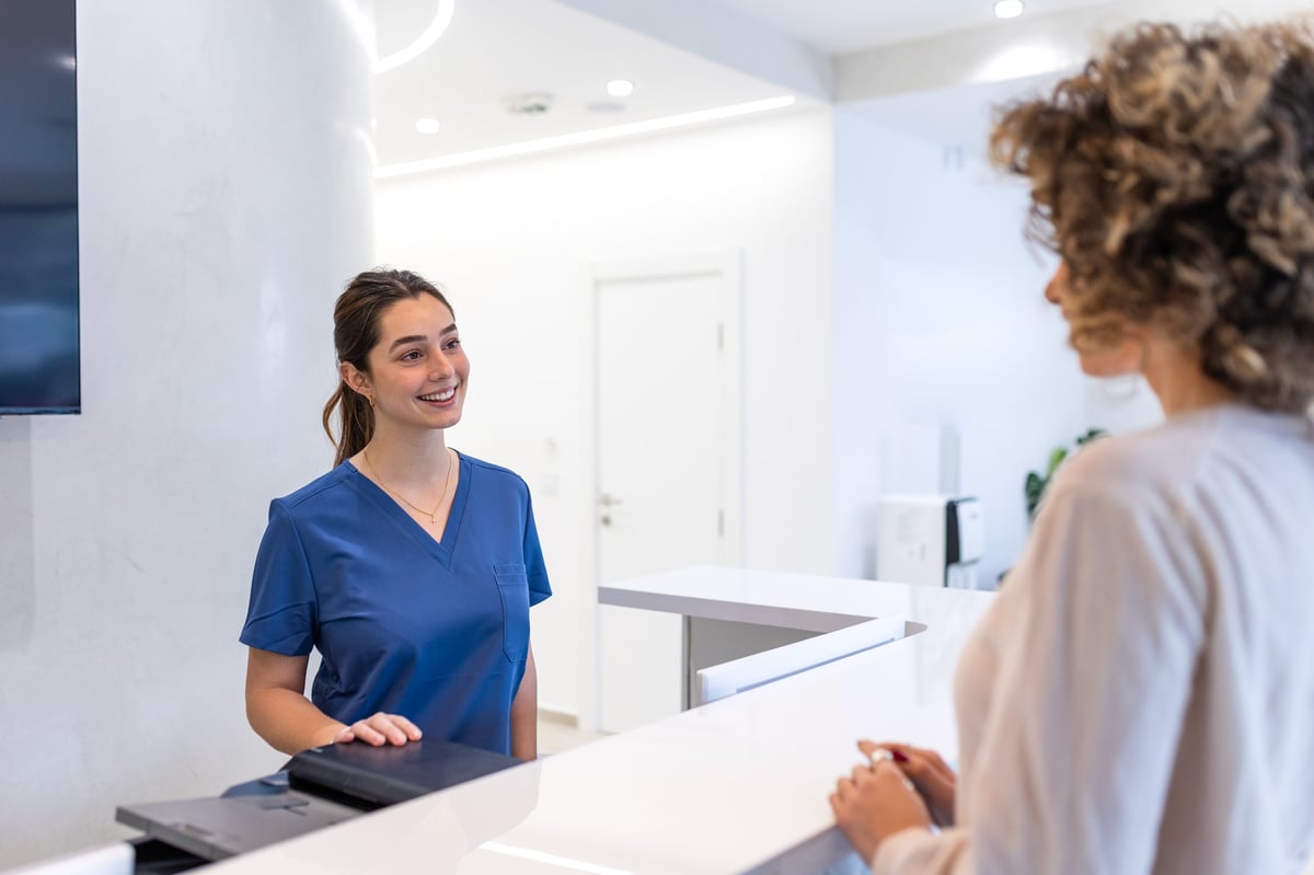 Medical receptionist welcoming patient at clinic for Wellness First Clinic