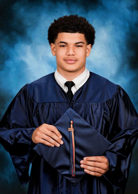 Young man in navy graduation gown and cap holding diploma against blue textured background